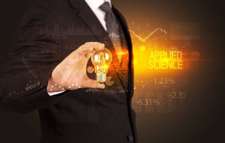 Foto de Empresario sosteniendo bombilla con inscripción APPLIED SCIENCE, concepto de tecnología empresarial - Imagen libre de derechos