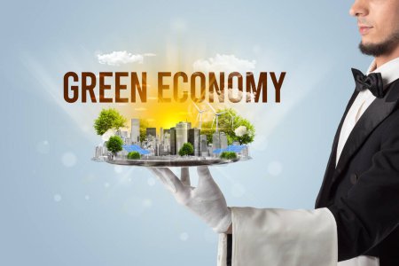 Photo for Waiter serving eco city with GREEN ECONOMY inscription, renewabke energy concept - Royalty Free Image