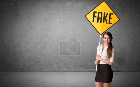Photo for Young business person holding road sign with FAKE inscription, new rules concept - Royalty Free Image