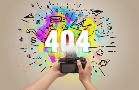 Photo for Close-up of a hand holding digital camera with abstract drawing and 404 inscription - Royalty Free Image