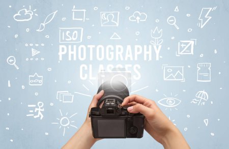 Photo for Hand taking picture with digital camera and PHOTOGRAPHY CLASSES inscription, camera settings concept - Royalty Free Image