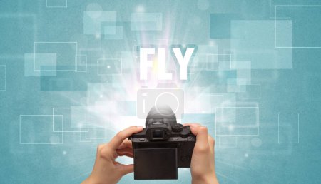 Téléchargez les photos : Gros plan d'un appareil photo numérique à main avec inscription FLY, concept de voyage - en image libre de droit