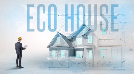 Téléchargez les photos : Jeune ingénieur tenant un plan avec inscription ECO HOUSE, concept de planification de la maison - en image libre de droit