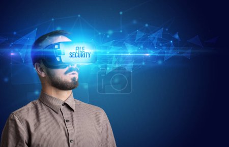 Téléchargez les photos : Homme d'affaires regardant à travers des lunettes de réalité virtuelle avec inscription FILE SECURITY, concept de cybersécurité - en image libre de droit