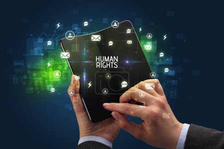 Foto de Empresario sosteniendo un smartphone plegable con inscripción de DERECHOS HUMANOS, concepto de redes sociales - Imagen libre de derechos
