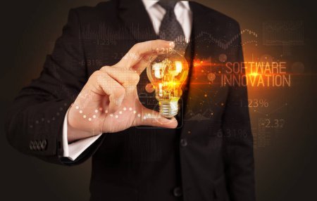 Téléchargez les photos : Homme d'affaires tenant une ampoule avec inscription LOGICIEL INNOVATION, concept de technologie d'entreprise - en image libre de droit