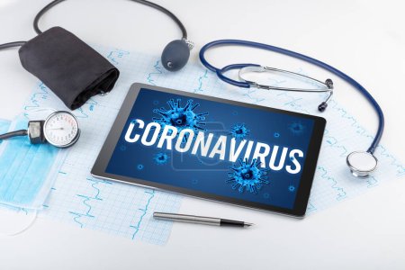 Foto de Tablet PC y herramientas médicas en superficie blanca con inscripción CORONAVIRUS, concepto pandémico - Imagen libre de derechos