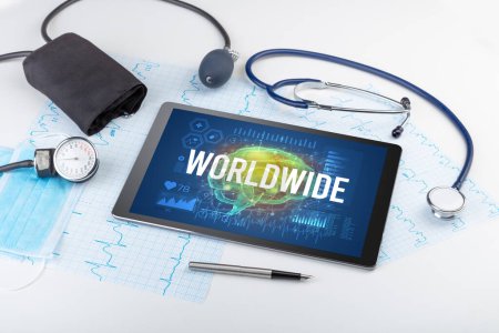 Foto de Tablet PC y herramientas médicas con inscripción WORLDWIDE, concepto de distanciamiento social - Imagen libre de derechos