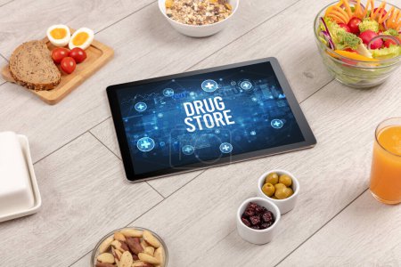 Téléchargez les photos : Concept DRUG STORE en comprimé PC avec des aliments sains autour, vue du dessus - en image libre de droit