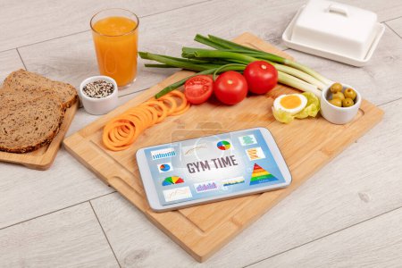 Foto de Alimento orgánico y tableta pc que muestra la inscripción GYM TIME, composición nutricional saludable - Imagen libre de derechos