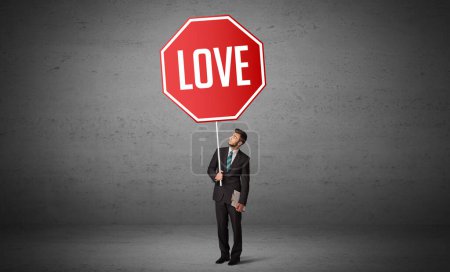 Téléchargez les photos : Jeune homme d'affaires tenant panneau routier avec inscription LOVE, nouveau concept de règles - en image libre de droit
