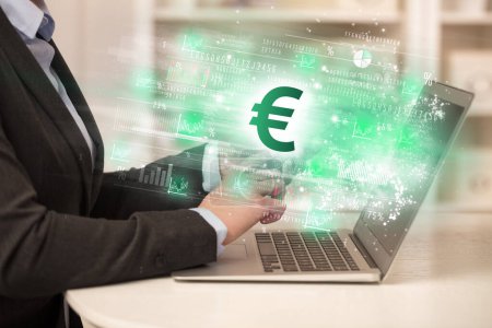 Téléchargez les photos : Jeune homme regardant le marché boursier sur ordinateur portable avec des icônes euro, concept de forex - en image libre de droit