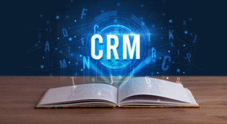 CRM inscription coming out from an open book, digital technology concept