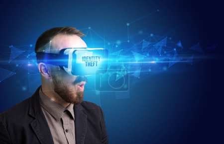 Foto de Hombre de negocios mirando a través de gafas de realidad virtual con inscripción IDENTITY THEFT, concepto de seguridad cibernética - Imagen libre de derechos