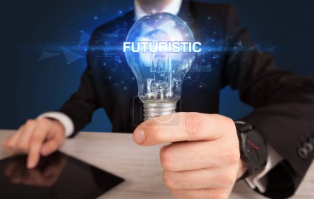 Foto de Empresario sosteniendo bombilla con inscripción FUTURÍSTICA, concepto de tecnología innovadora - Imagen libre de derechos