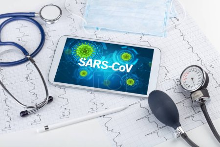 Foto de Vista de cerca de una tableta PC con inscripción SARS-CoV, concepto de microbiología - Imagen libre de derechos