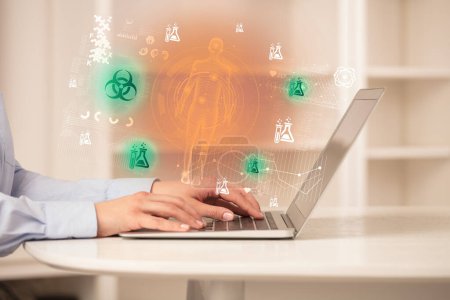 Téléchargez les photos : Médecin travaillant sur un ordinateur portable avec des icônes de risque biologique qui en sortent, concept de soins de santé - en image libre de droit