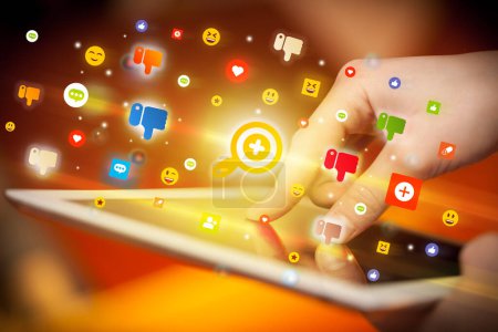 Foto de Primer plano de una mano usando tableta con iconos de lupa de colores que salen de ella, concepto de redes sociales - Imagen libre de derechos