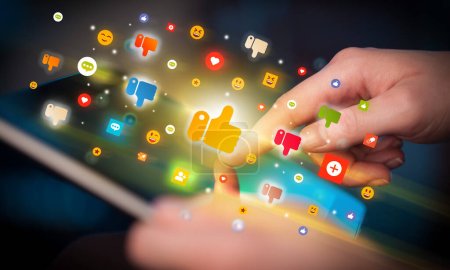 Foto de Primer plano de una mano usando tableta con iconos coloridos como saliendo de ella, concepto de redes sociales - Imagen libre de derechos