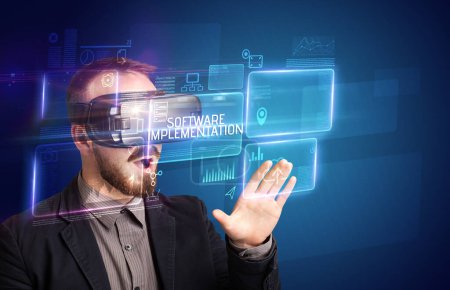 Foto de Hombre de negocios mirando a través de gafas de realidad virtual con inscripción SOFTWARE IMPLEMENTACIÓN, concepto de nueva tecnología - Imagen libre de derechos