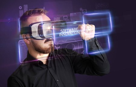 Téléchargez les photos : Homme d'affaires regardant à travers des lunettes de réalité virtuelle avec inscription LOGICIEL INNOVATION, nouveau concept technologique - en image libre de droit