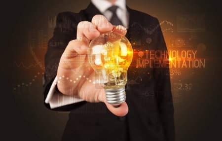 Foto de Empresario sosteniendo bombilla con TECNOLOGÍA EJECUCIÓN inscripción, Concepto de tecnología empresarial - Imagen libre de derechos