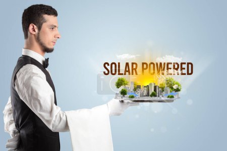 Foto de Camarero sirviendo eco ciudad con inscripción SOLAR POWERED, concepto de energía renovable - Imagen libre de derechos