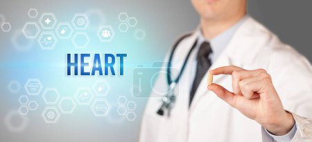 Téléchargez les photos : Gros plan d'un médecin vous donnant une pilule avec inscription HEART, concept médical - en image libre de droit