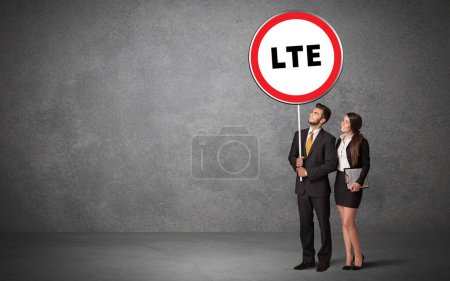 Téléchargez les photos : Jeune homme d'affaires holdig panneau de signalisation avec abréviation LTE, concept de solution technologique - en image libre de droit