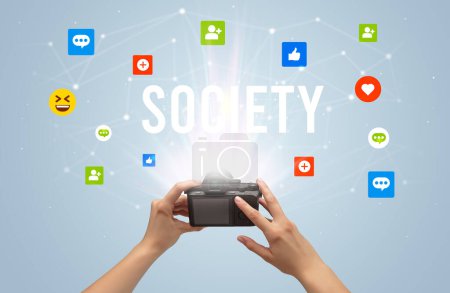 Téléchargez les photos : Utiliser la caméra pour capturer le contenu des médias sociaux avec l'inscription SOCIETY, concept de contenu des médias sociaux - en image libre de droit