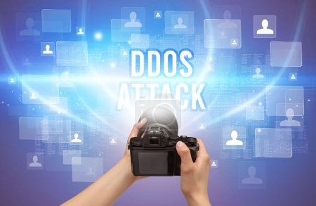 Téléchargez les photos : Gros plan de la caméra portative avec inscription DDOS ATTACK, concept de vidéosurveillance - en image libre de droit
