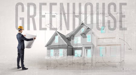 Photo for Young engineer holding blueprint with GREENHOUSE inscription, house planning concept - Royalty Free Image