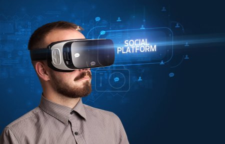 Téléchargez les photos : Homme d'affaires regardant à travers des lunettes de réalité virtuelle avec inscription PLATEFORME SOCIALE, concept de réseautage social - en image libre de droit