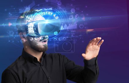 Téléchargez les photos : Homme d'affaires regardant à travers des lunettes de réalité virtuelle avec inscription INDUSTRY 4.0, concept technologique innovant - en image libre de droit
