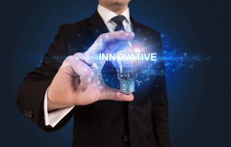 Foto de Empresario sosteniendo bombilla con inscripción INNOVATIVA, concepto de tecnología innovadora - Imagen libre de derechos