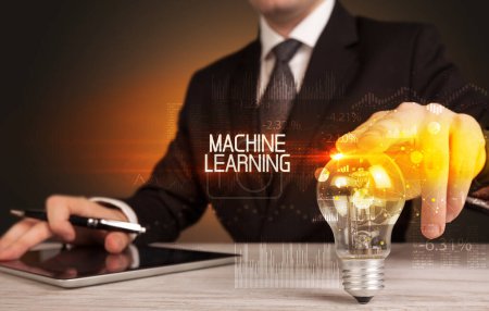 Téléchargez les photos : Homme d'affaires tenant ampoule avec inscription MACHINE LEARNING, concept de technologie d'entreprise - en image libre de droit