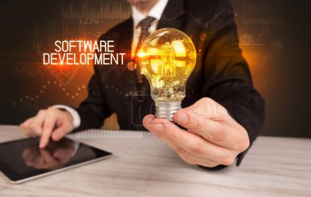 Photo for Businessman holding lightbulb with SOFTWARE DEVELOPMENT inscription, Business technology concept - Royalty Free Image