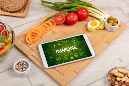Foto de Composición de Tablet PC saludable con inscripción INMUNE, concepto de refuerzo del sistema inmunológico - Imagen libre de derechos