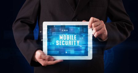 Photo for Young business person working on tablet and shows the digital sign: MOBILE SECURITY - Royalty Free Image