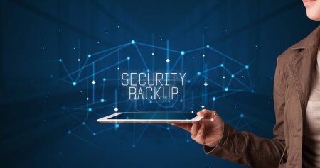 Photo for Young business person working on tablet and shows the digital sign: SECURITY BACKUP - Royalty Free Image