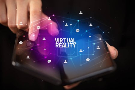 Photo for Businessman holding a foldable smartphone with VIRTUAL REALITY inscription, new technology concept - Royalty Free Image