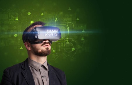 Téléchargez les photos : Homme d'affaires regardant à travers des lunettes de réalité virtuelle avec inscription des droits de l'homme, concept de réseautage social - en image libre de droit