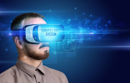 Téléchargez les photos : Homme d'affaires regardant à travers des lunettes de réalité virtuelle avec inscription SURVEILLANCE SYSTEM, concept de cybersécurité - en image libre de droit