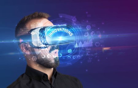 Téléchargez les photos : Homme d'affaires regardant à travers des lunettes de réalité virtuelle avec inscription INNOVATIONS, concept technologique innovant - en image libre de droit