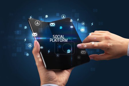 Foto de Empresario sosteniendo un smartphone plegable con inscripción PLATAFORMA SOCIAL, concepto de redes sociales - Imagen libre de derechos
