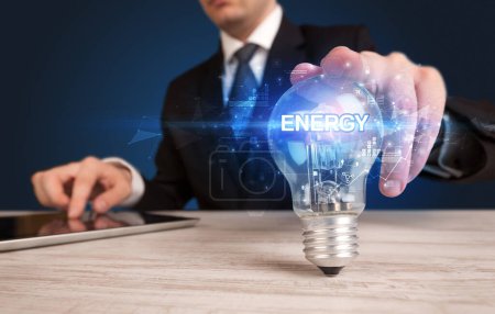 Foto de Empresario sosteniendo bombilla con inscripción ENERGY, concepto de tecnología innovadora - Imagen libre de derechos