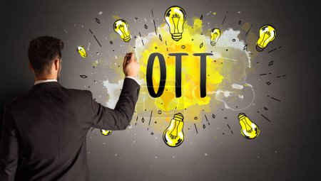Foto de Hombre de negocios dibujo bombilla de colores con OTT abreviatura, concepto de idea de nueva tecnología - Imagen libre de derechos