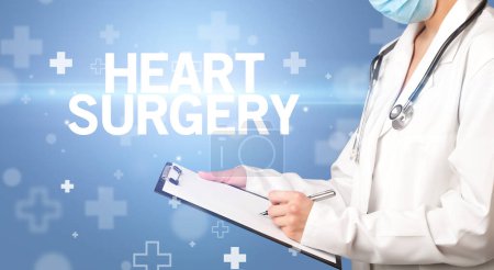 Téléchargez les photos : Médecin écrit des notes sur le presse-papiers avec inscription HEART SURGERY, concept de premiers soins - en image libre de droit