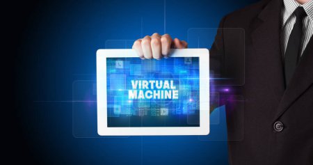 Photo for Young business person working on tablet and shows the inscription: VIRTUAL MACHINE - Royalty Free Image