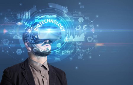 Homme d'affaires regardant à travers des lunettes de réalité virtuelle avec inscription BIOTECHNOLOGY, concept technologique innovant